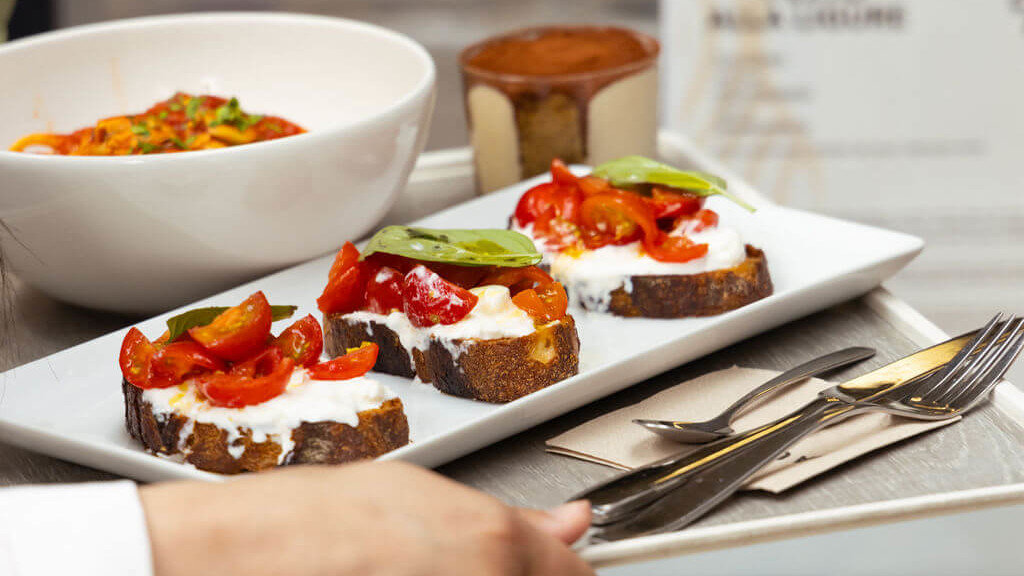 Plateau de bruschettas aux tomates cerises et basilic, servi avec un bol de pâtes et un dessert au restaurant de La Commune, Lyon.